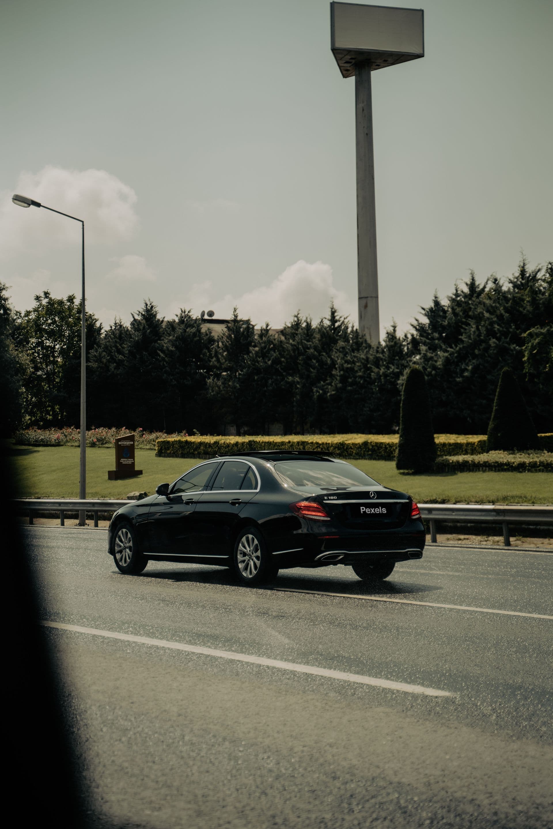 Black sedan on a tree-lined road, Adelaide Airport suburb-by-suburb drive-time guide