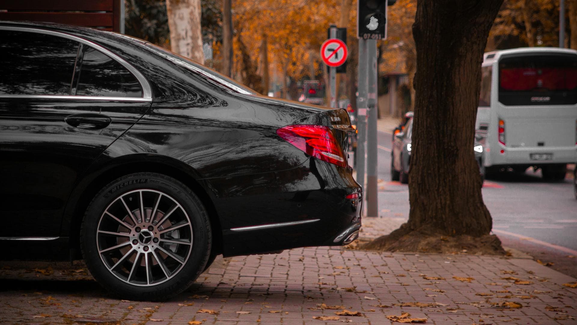 Black Mercedes sedan in autumn streetscape, Adelaide chauffeured vehicle fleet