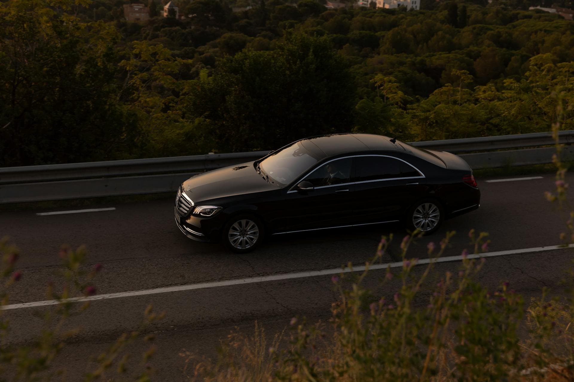 Black luxury sedan driving on a picturesque forest road, Adelaide service locations