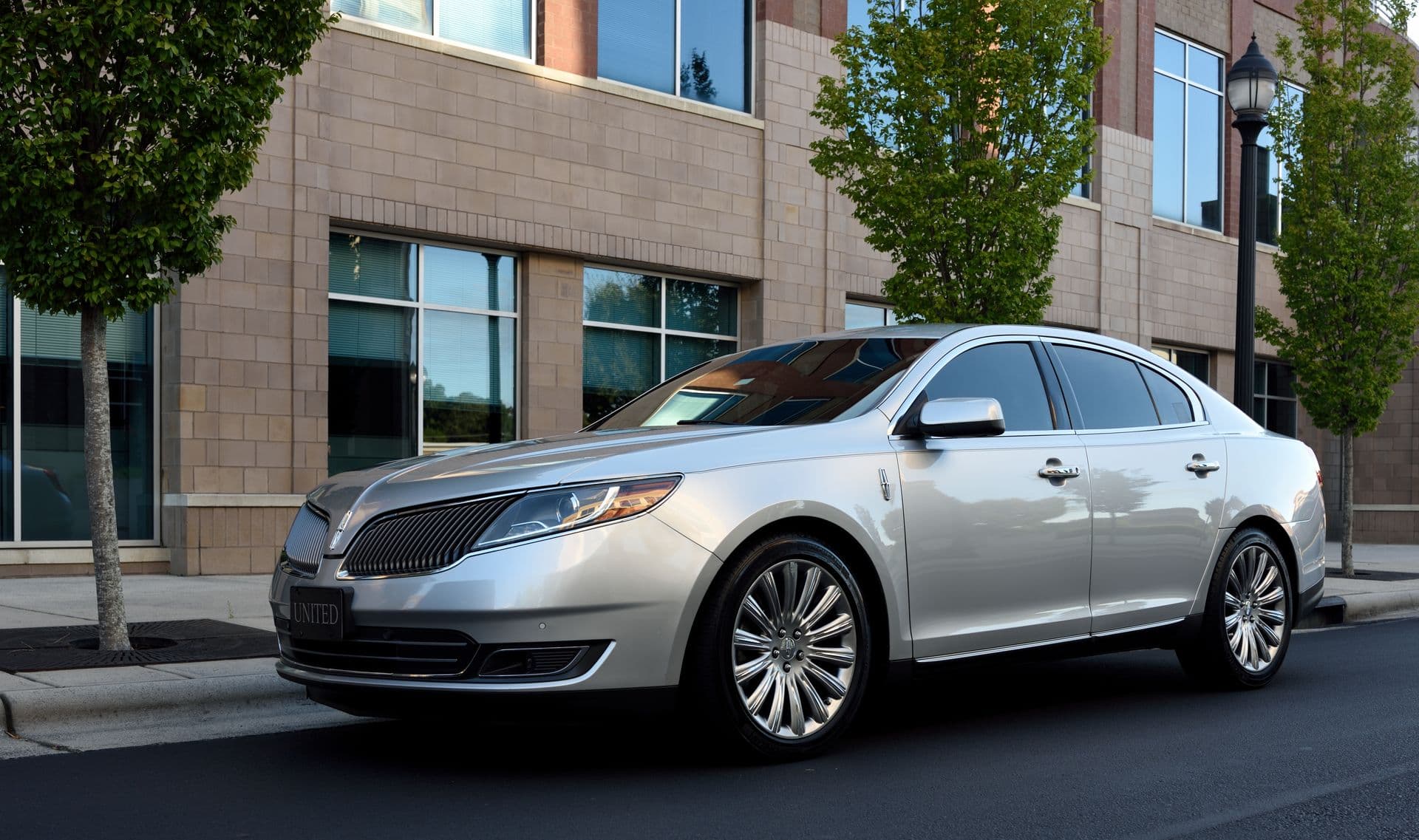 Silver luxury sedan beside modern urban building, Adelaide chauffeur services overview