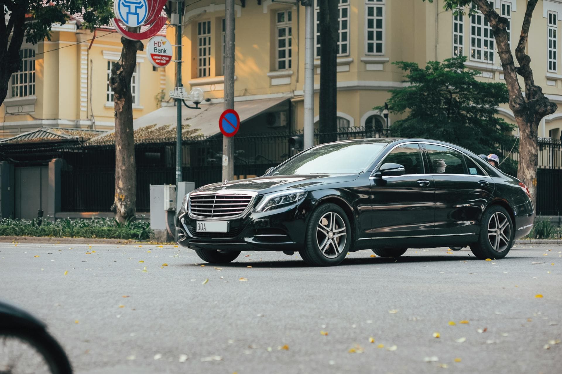 Black sedan navigating historic urban street near event venue, Adelaide special-event chauffeur